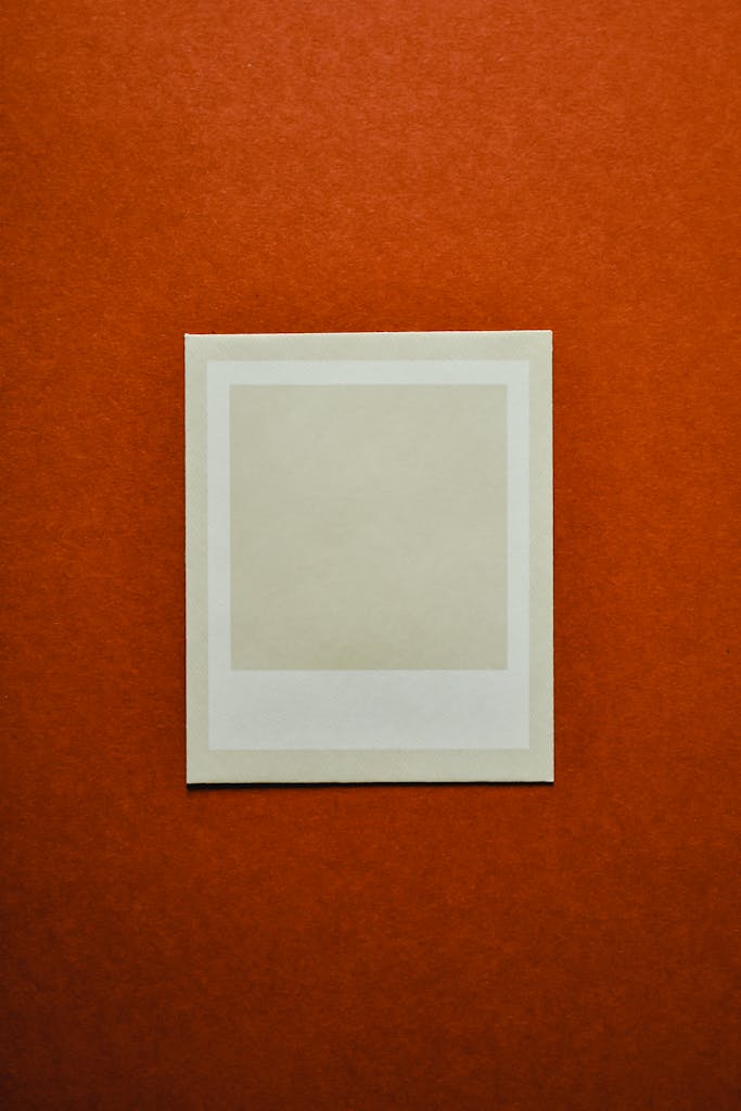 A blank instant film frame displayed on a vibrant orange background, perfect for mockups.