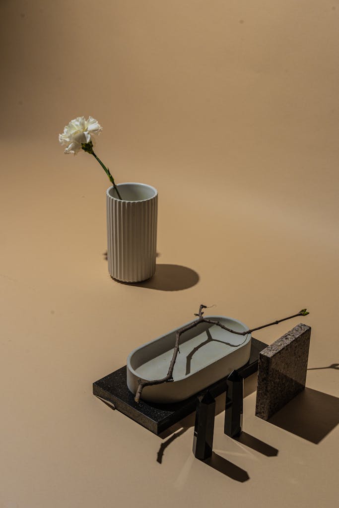 Minimalist still life with a white flower in a ceramic vase on a neutral backdrop.